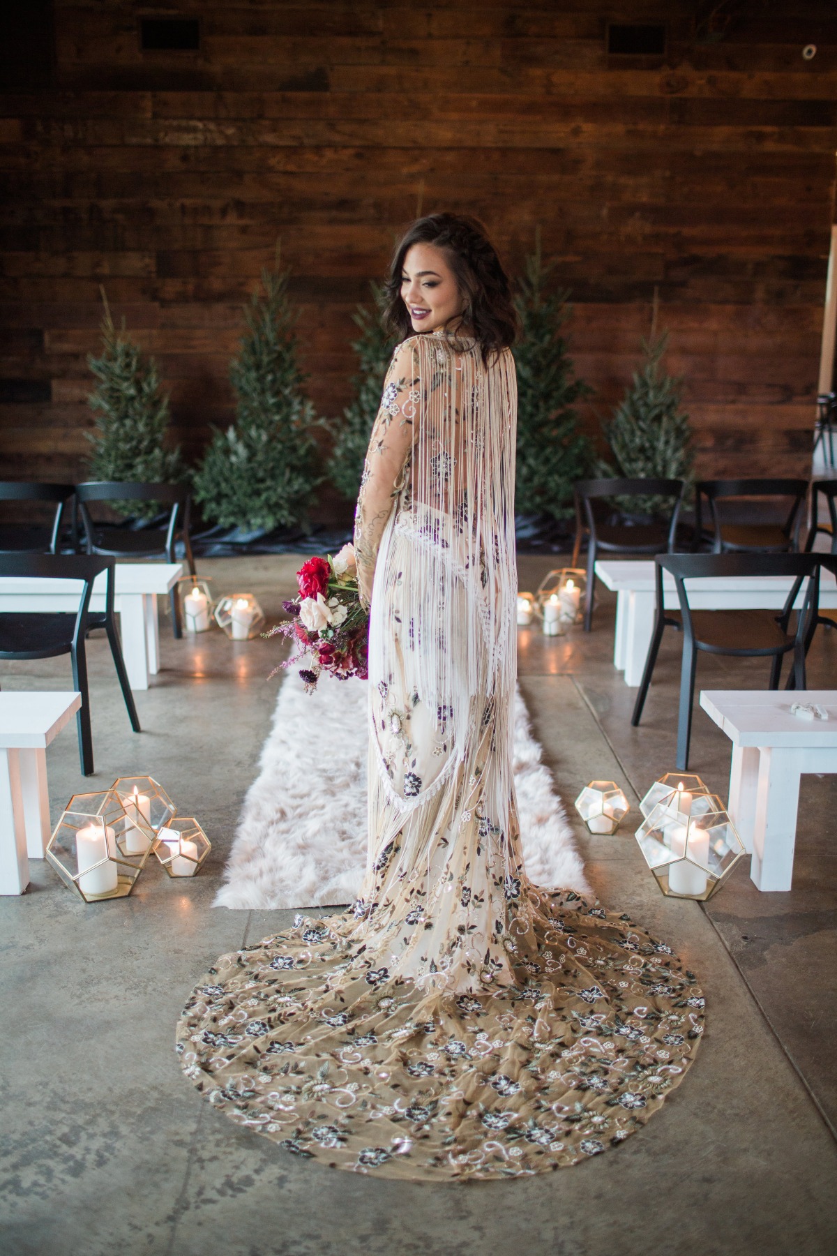 Elegant bride in a shimmering gown smiles, wedding decor in background