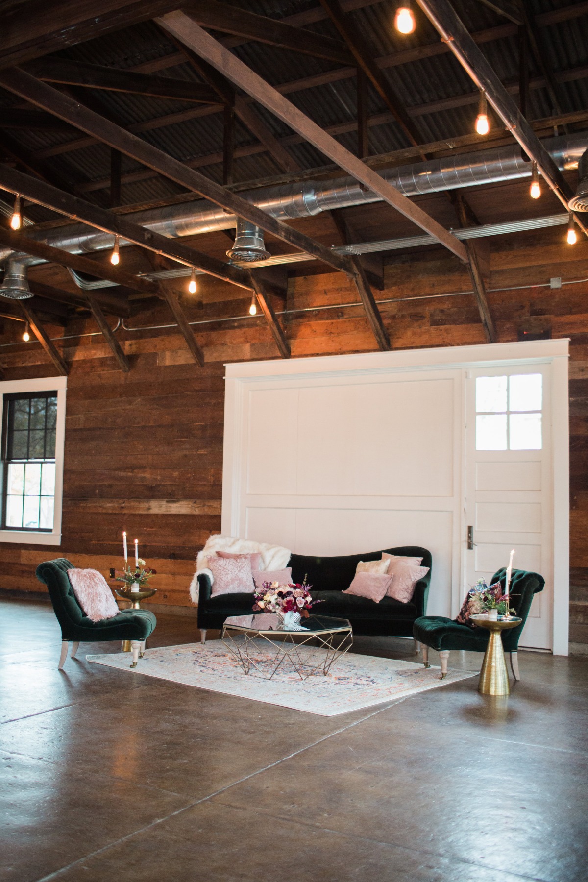 Elegant lounge furniture setup with flowers and rug under light bulbs