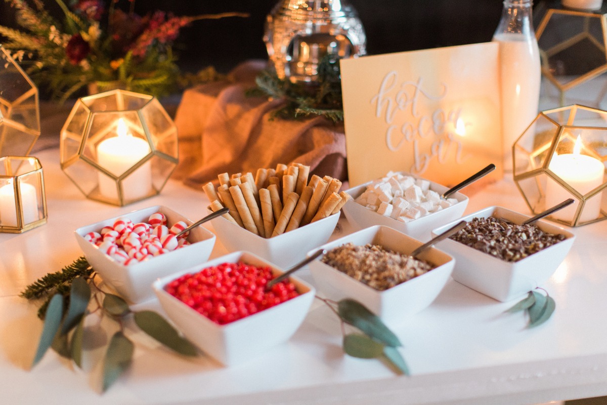 Hot cocoa bar with various toppings and candles for a cozy vibe