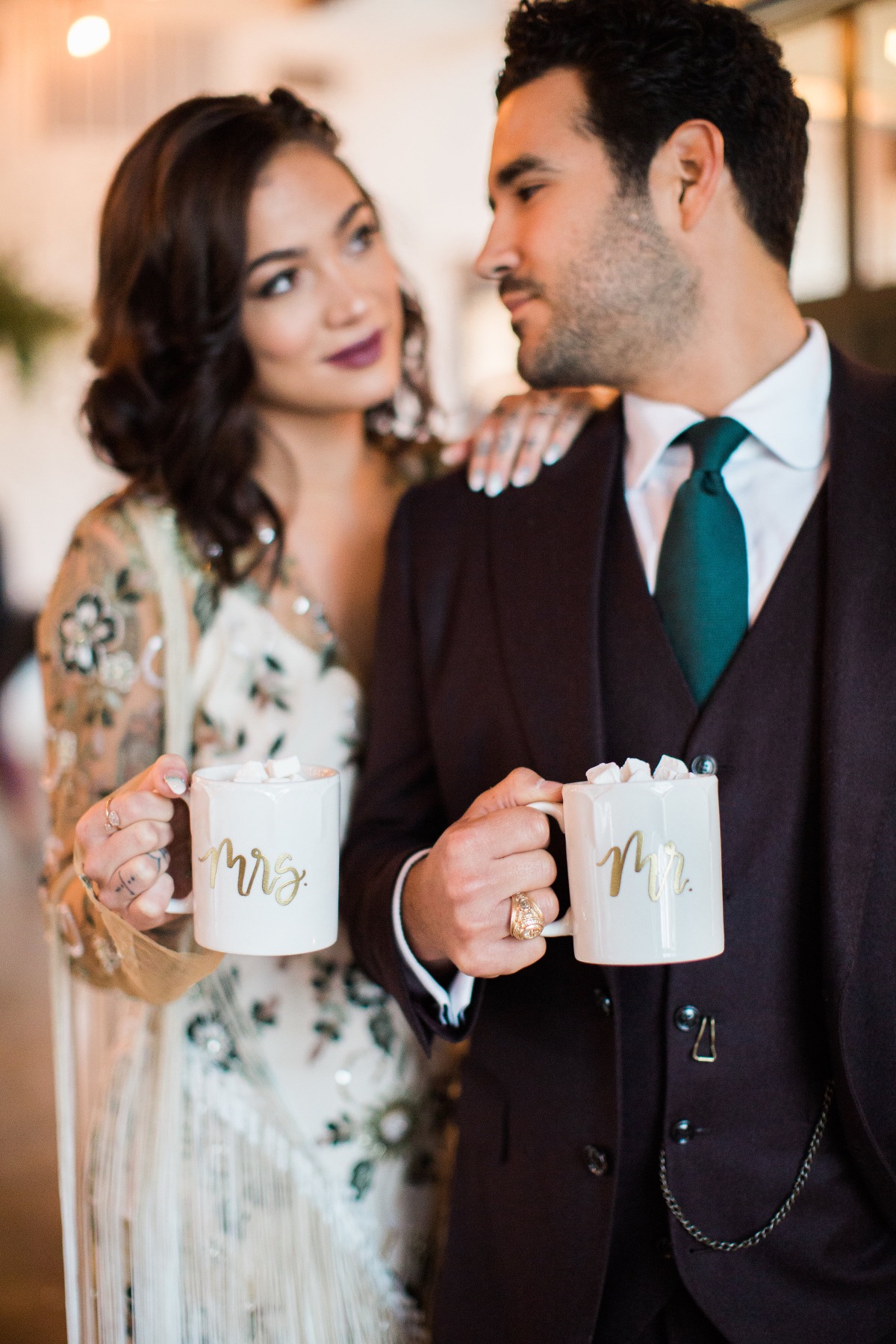 Newlyweds holding Mr and Mrs mugs, looking at each other lovingly