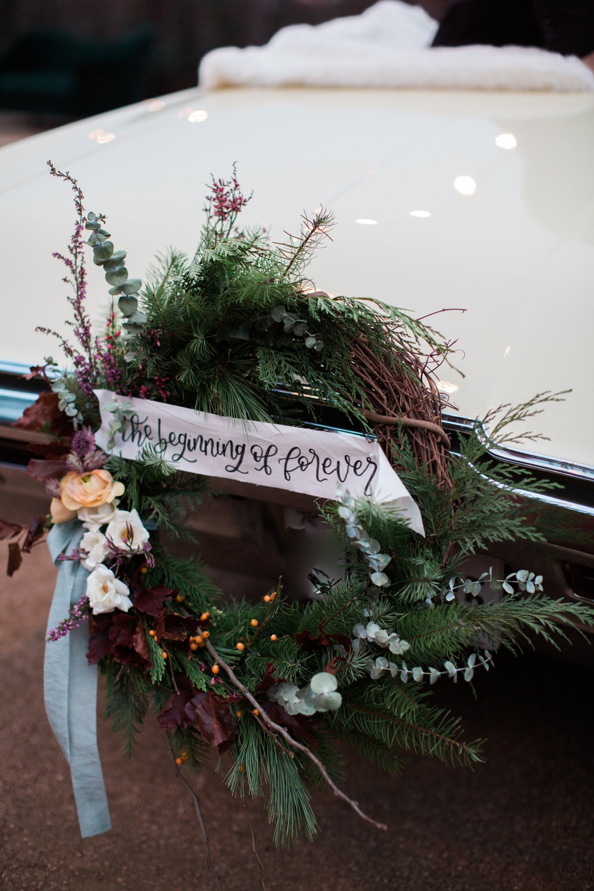 Wedding car decorated with a floral wreath and a beginning of forever sign