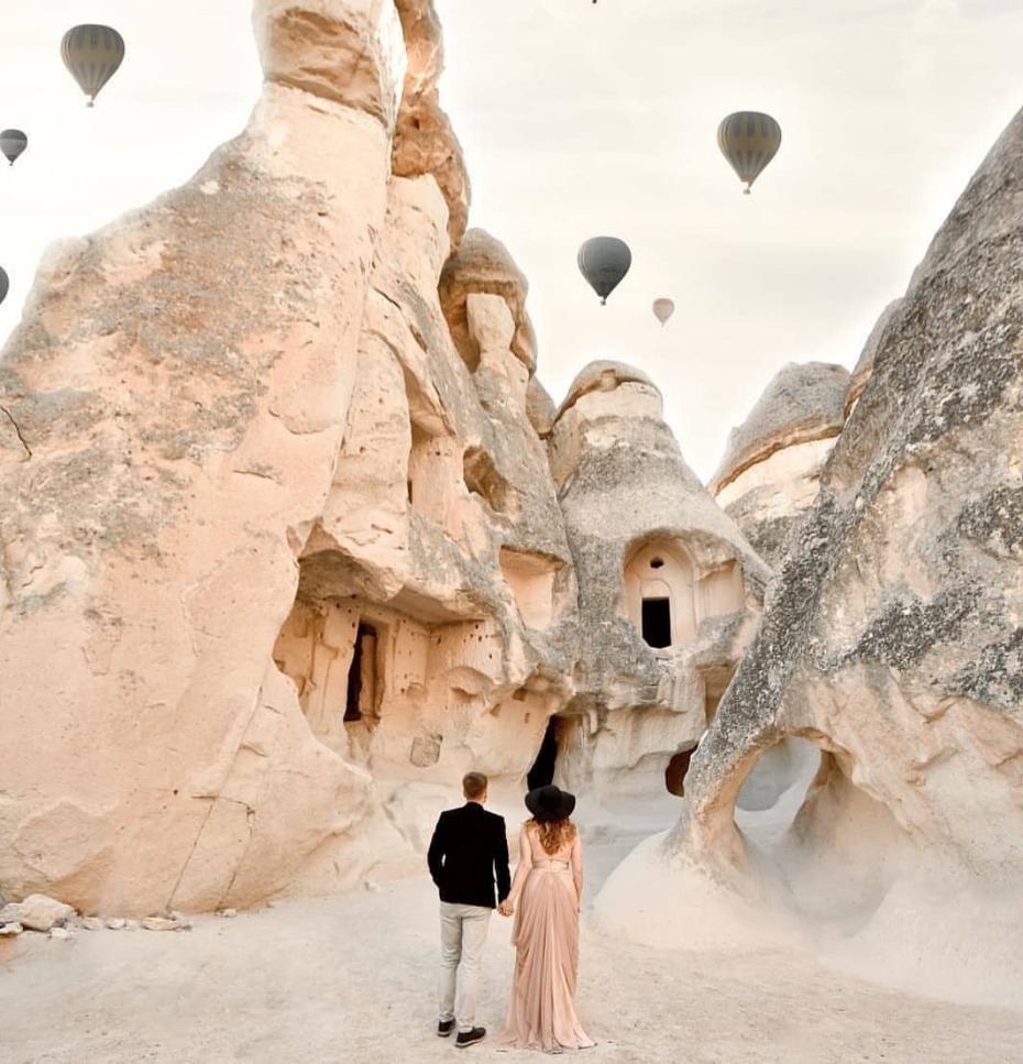 Engagement photos in between sand/mountain huts with hot air balloons