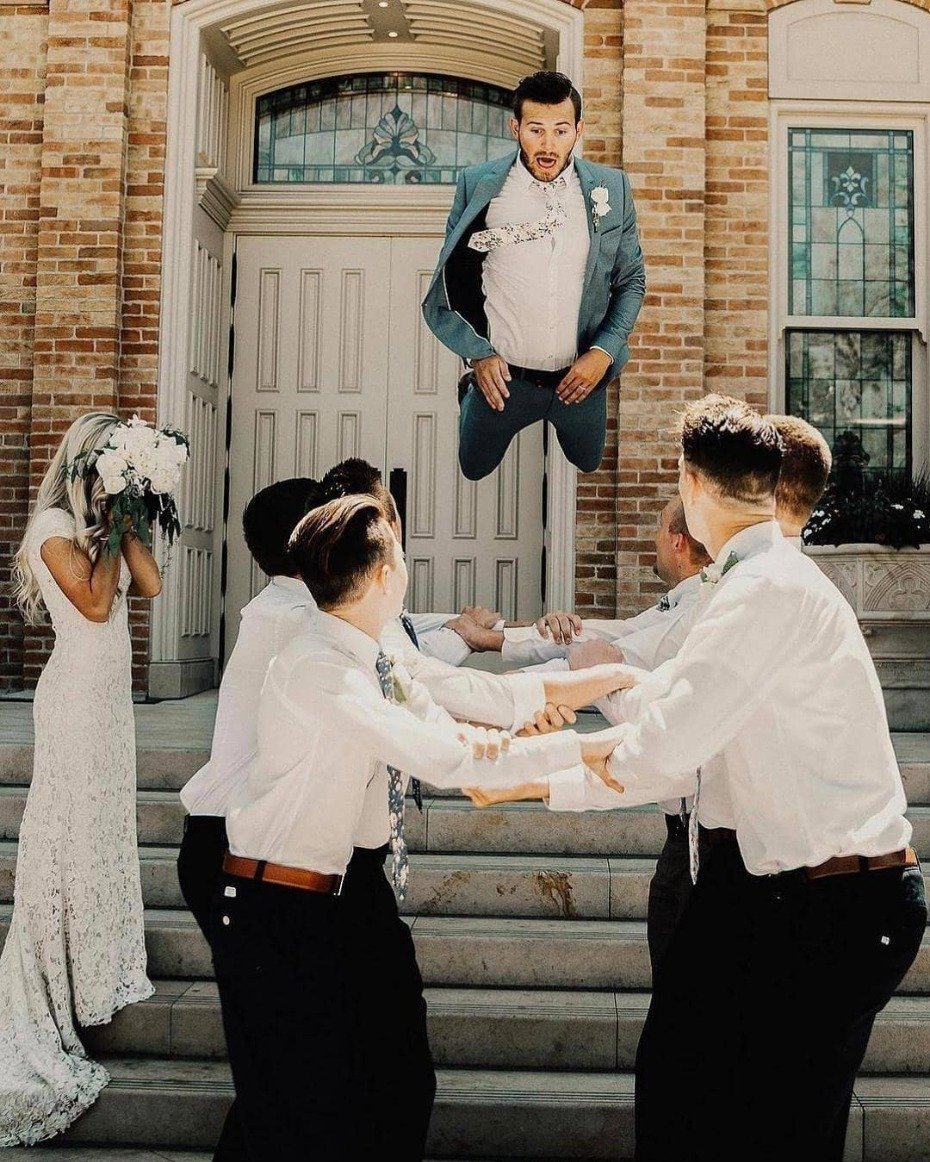 Groom jumping onto bridge made by groomsmen with scared bride beside him