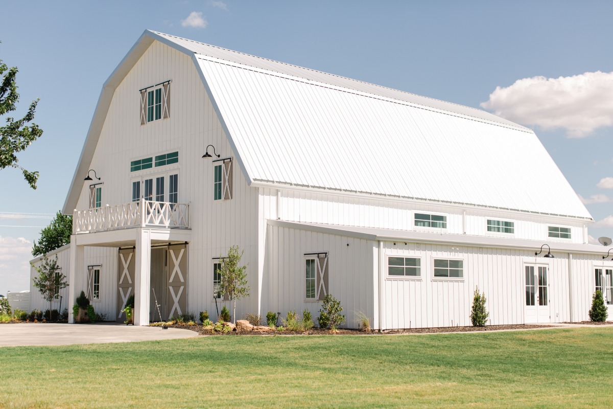 White modern barn venue with a grass lawn and blue sky