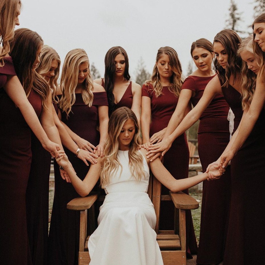 Bride praying and holding hands with her bridesmaids before ceremony
