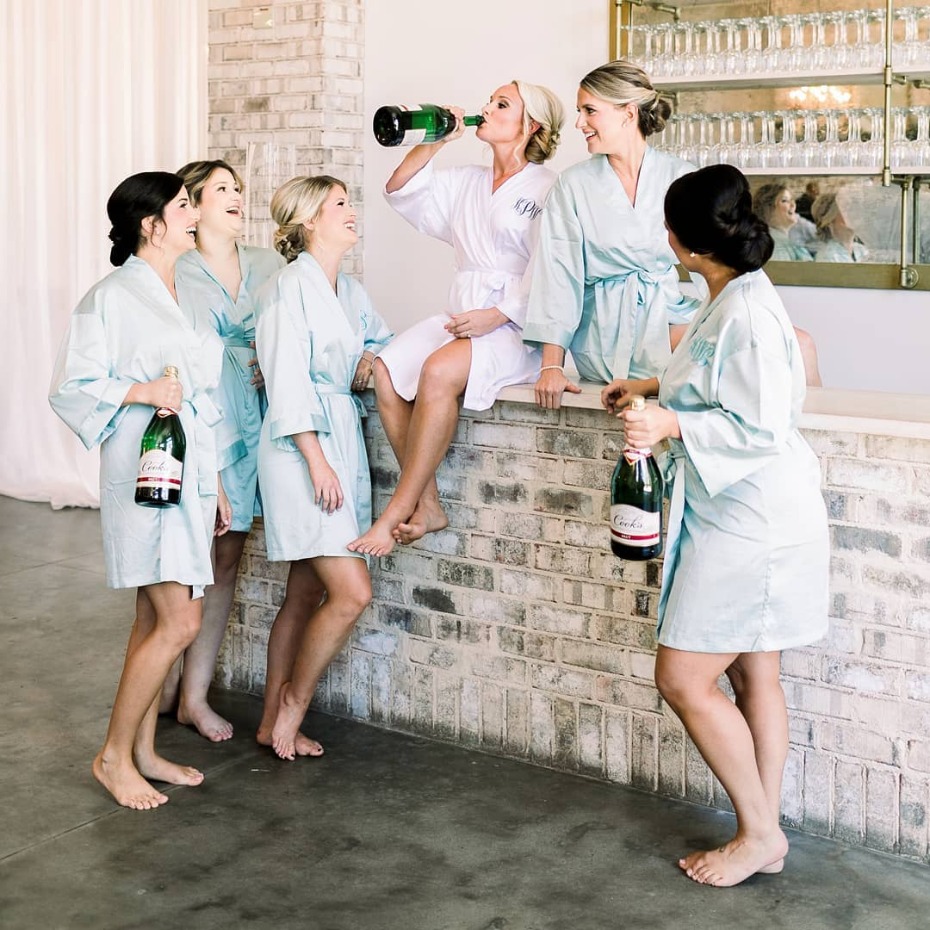 Bride and her bridesmaids drinking champagne in robes