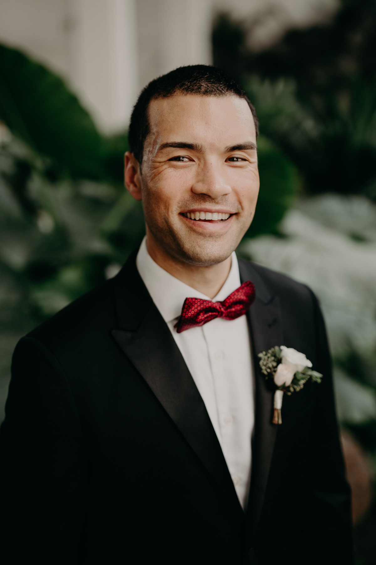 groom in tux with red bow tie