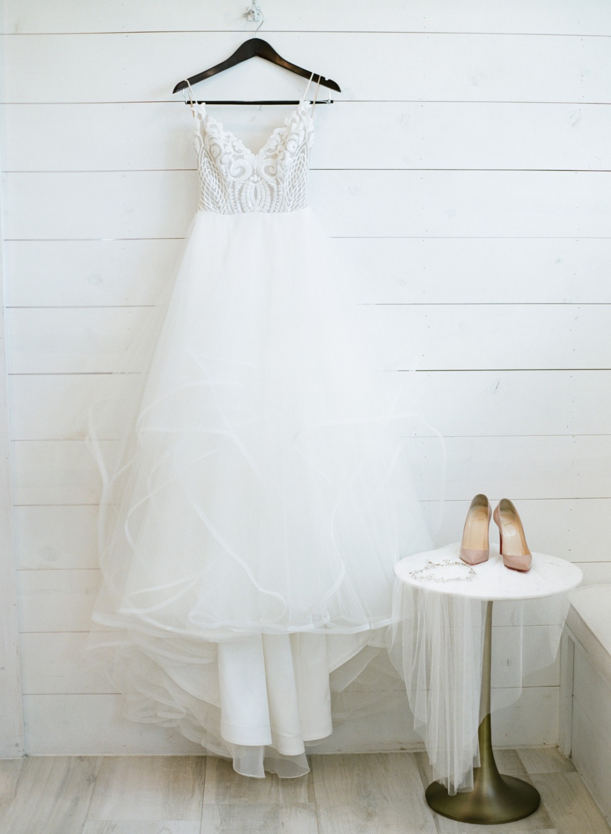 Elegant white wedding dress hanging with shoes and veil