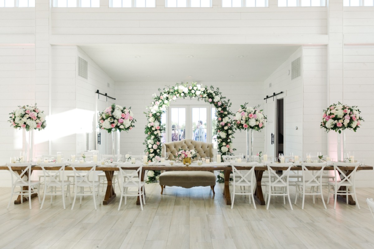 Elegant wedding reception decorated with floral arrangements and white chairs