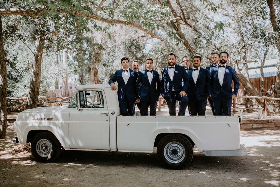 Groomsmen in truck wearing navy suits and bow ties