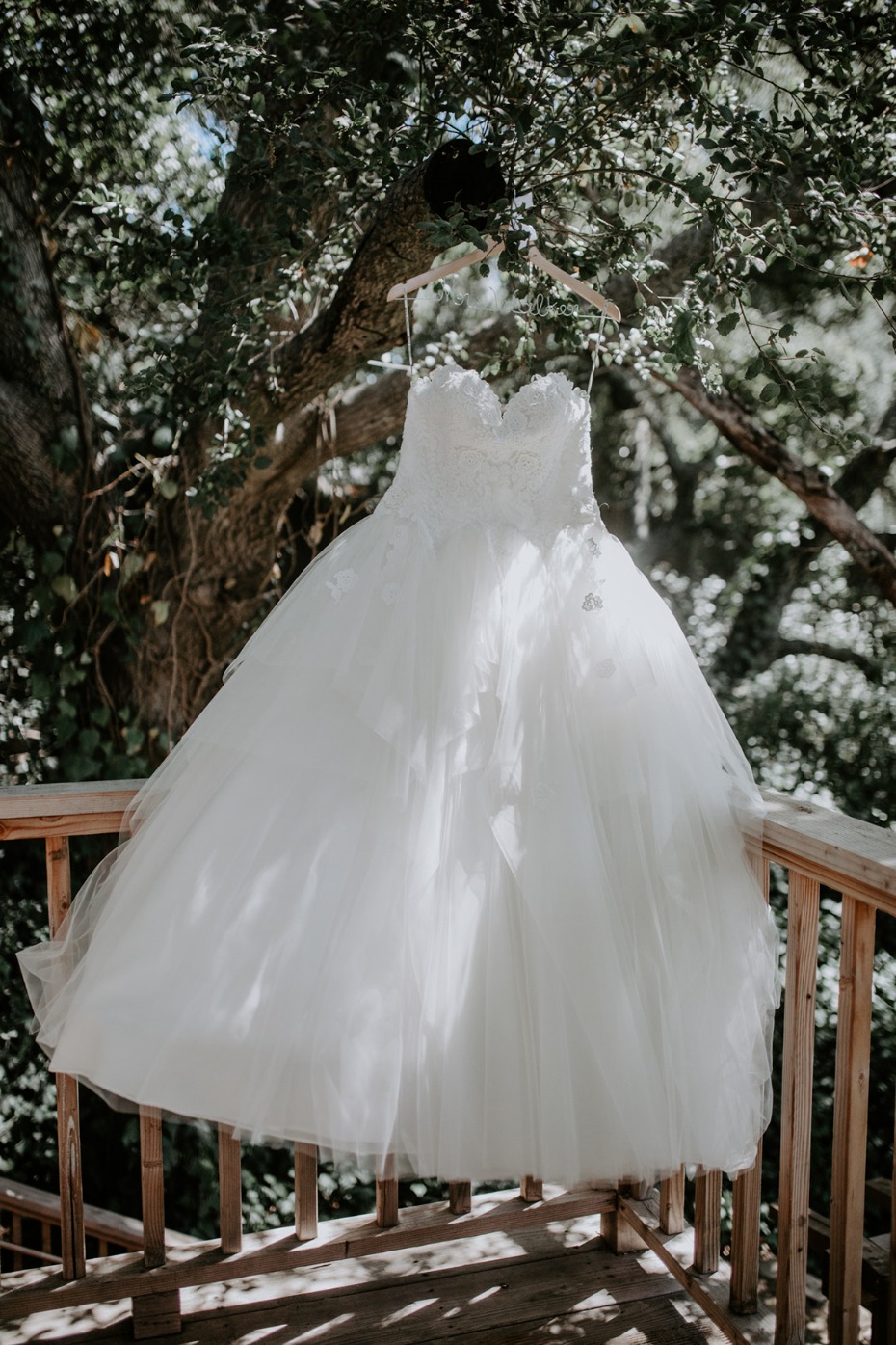 White wedding dress hanging outdoor on a wooden porch