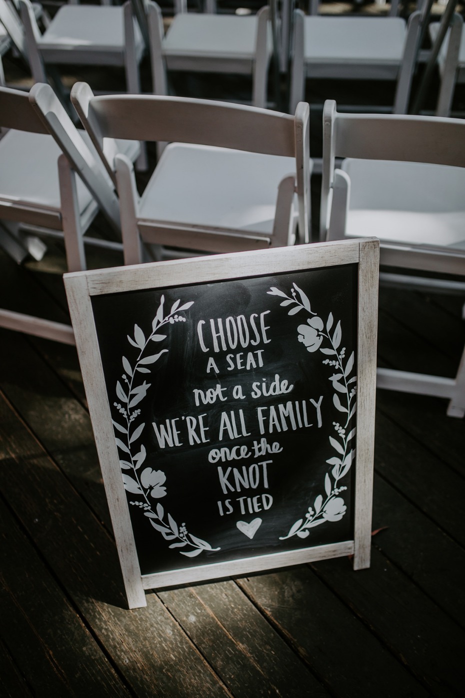 Wedding sign asking guests to choose a seat, not a side, with chairs