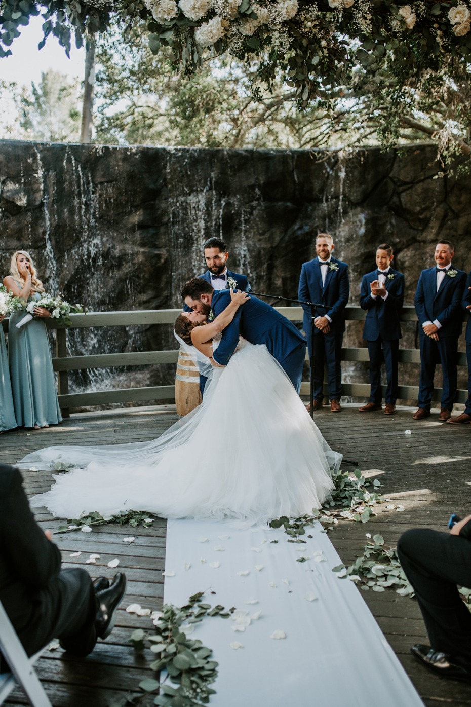 A happy couple shares a passionate kiss at their outdoor wedding ceremony