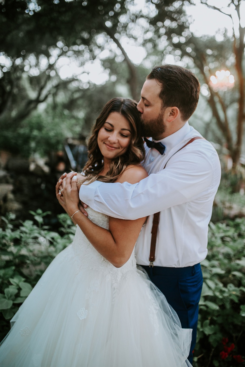 Bride and groom embrace in outdoor wedding portrait