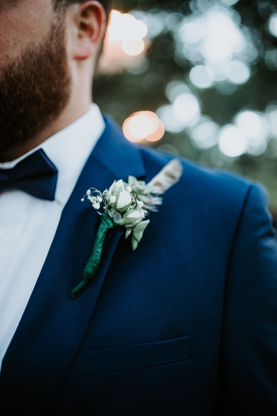 Groom in navy suit with boutonniere at wedding ceremony