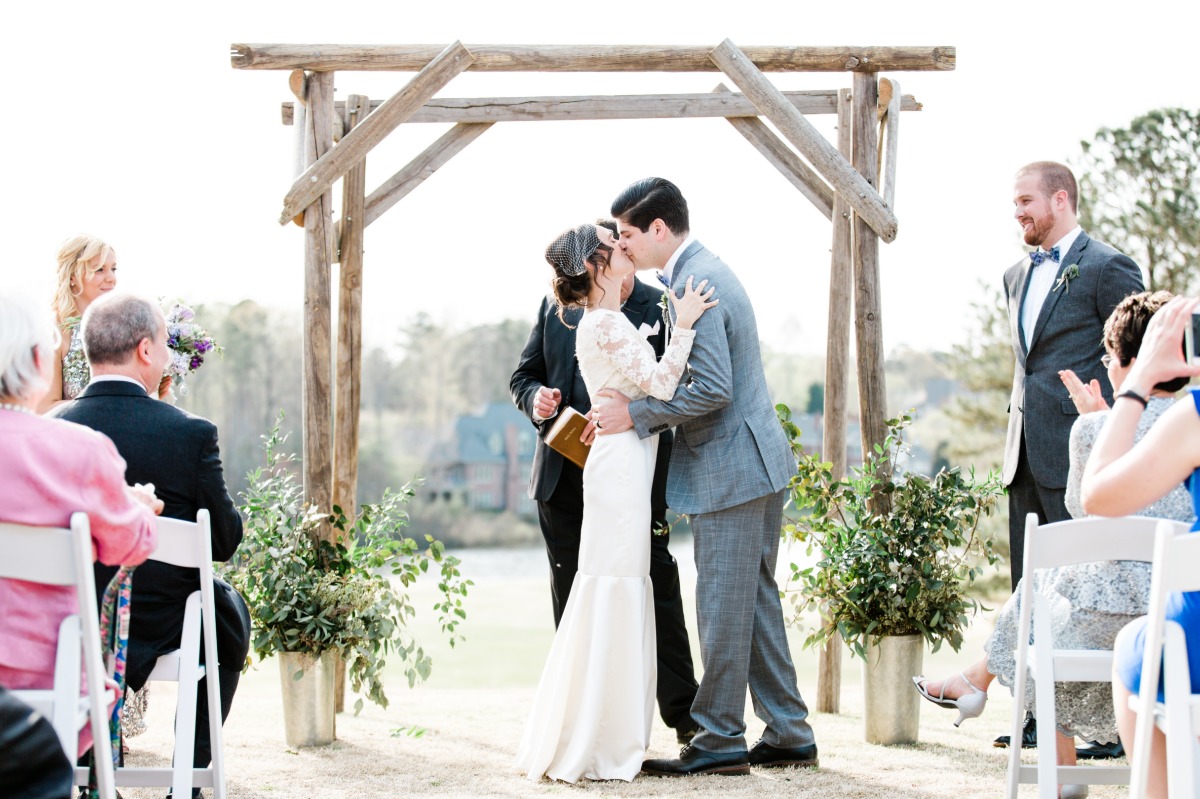 Bride and groom kissing at outdoor wedding ceremony