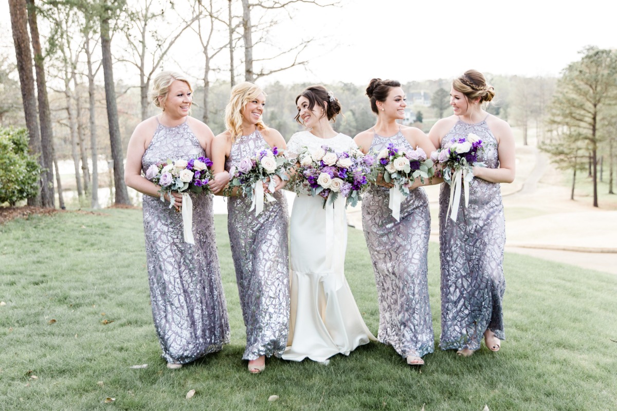 Happy bride with bridesmaids in silver gowns at wedding