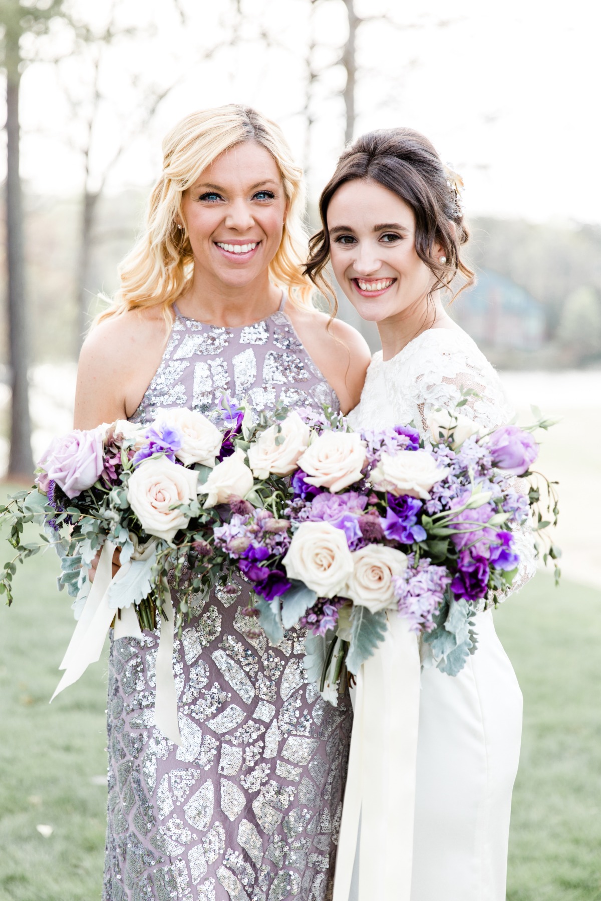 Smiling bridesmaid and bride holding rose bouquets
