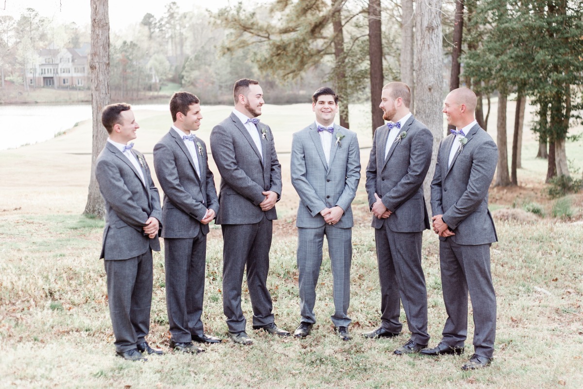 Groomsmen in grey suits and bow ties at outdoor wedding