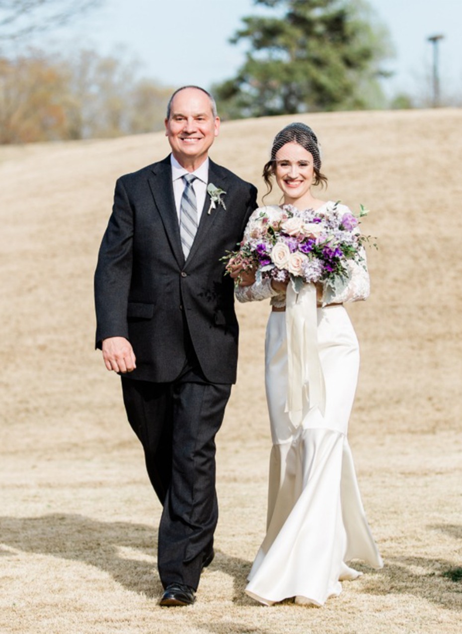 Father and bride with bouquet walk at wedding outdoors