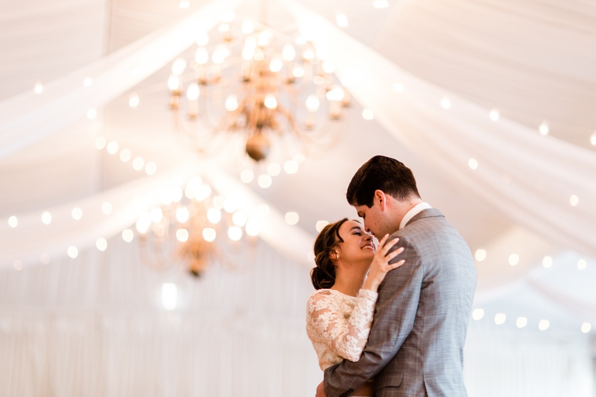 Newlyweds share a tender moment during their first dance under lights