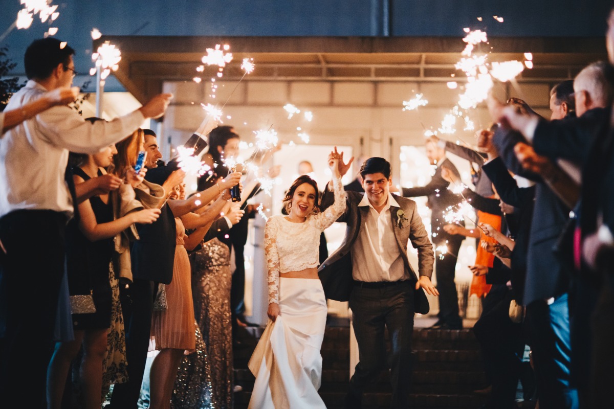 Newlyweds run through sparklers as guests celebrate their wedding