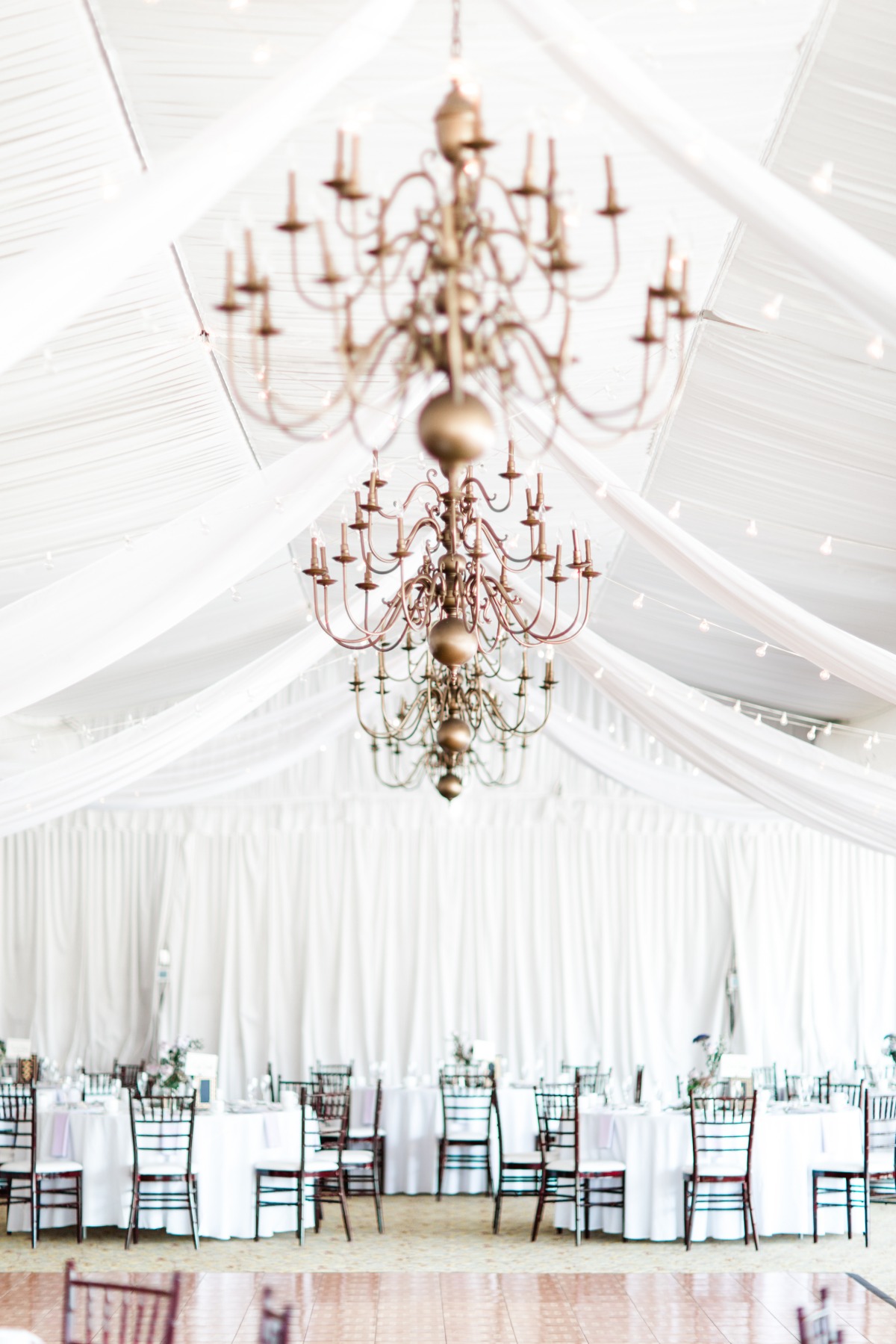 Elegant gold chandeliers above wedding reception tables