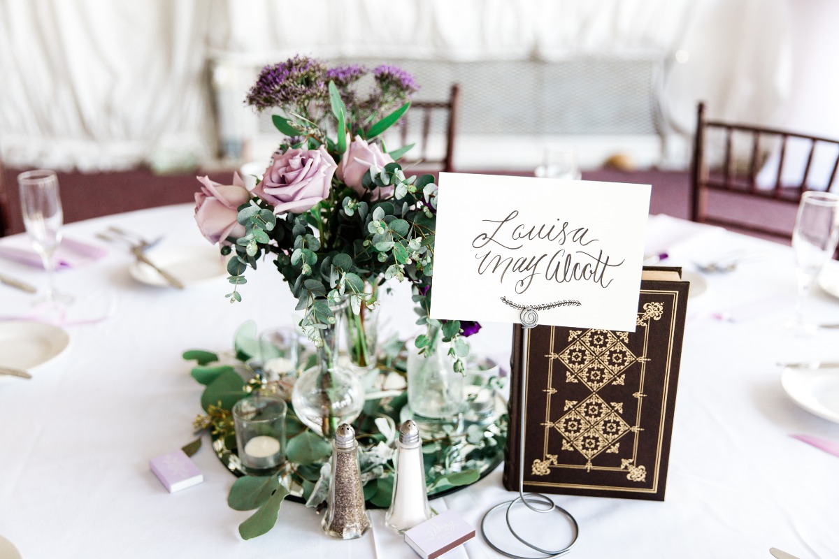 Wedding table setting with purple roses and Louisa May Alcott name card