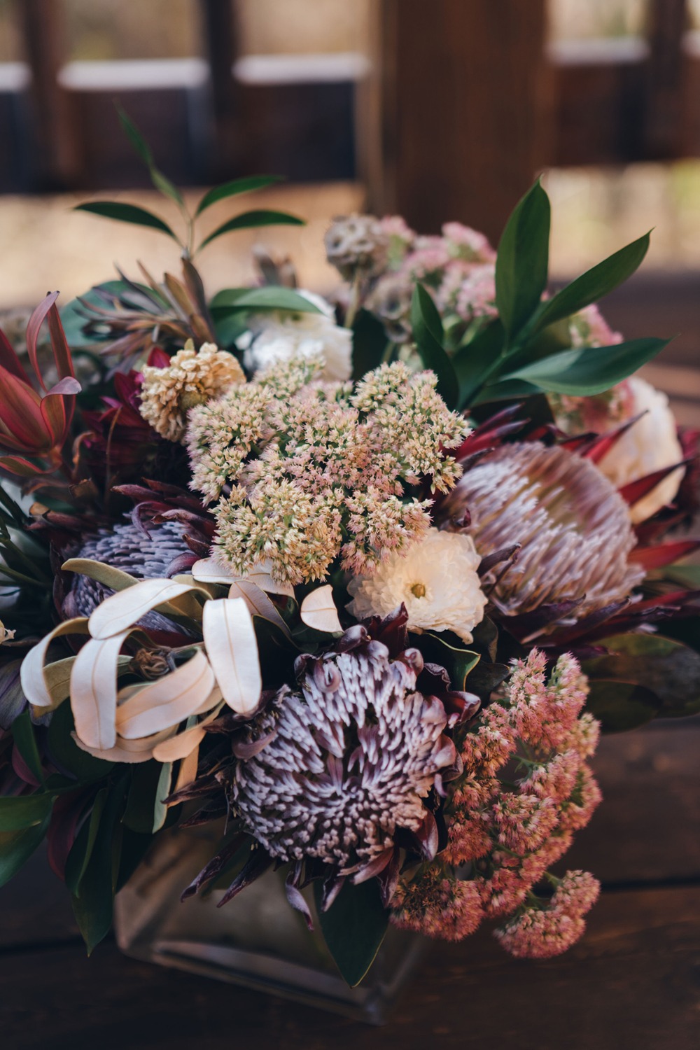 Close-up of a vibrant and artistic floral arrangement on a wooden surface