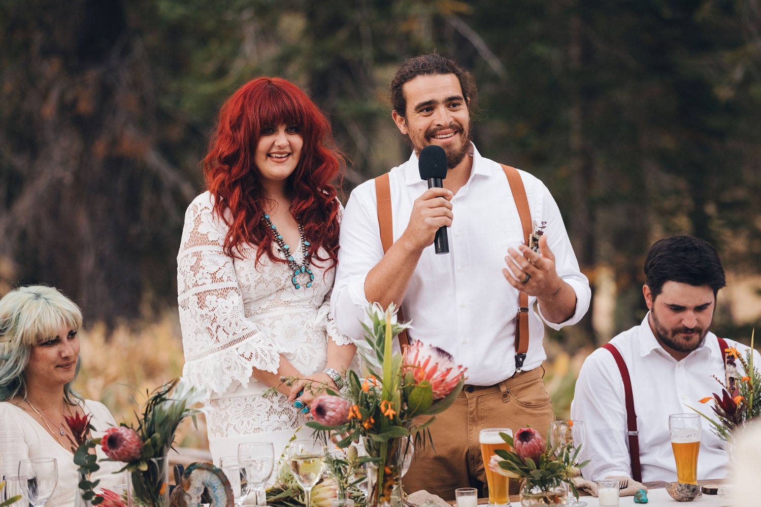 A groom making a toast at an outdoor wedding reception with a bride