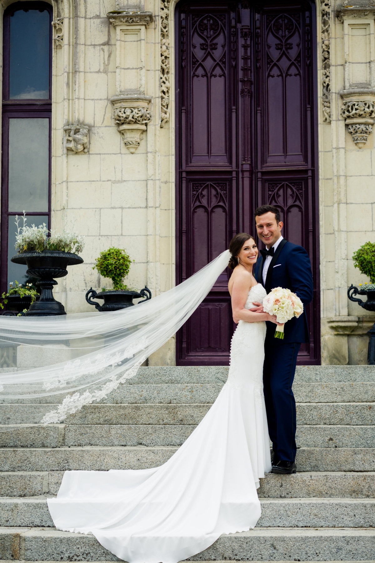 Bride and groom pose on steps in front of a stately door
