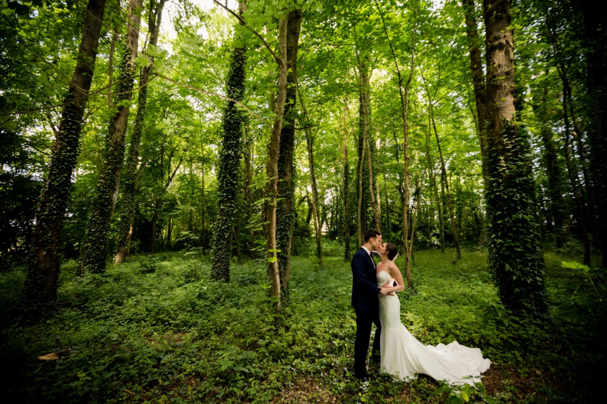 Wedding couple kissing in a lush green forest setting