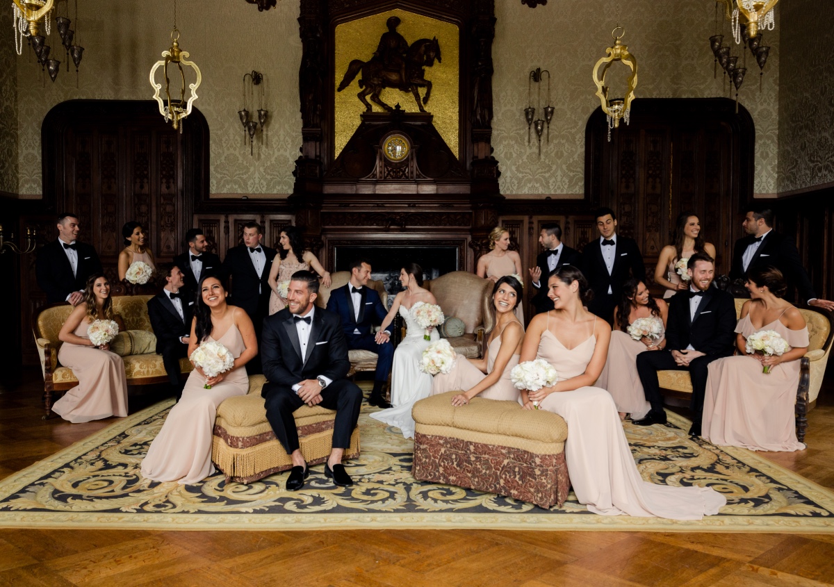 Wedding party posing in a luxurious mansion interior, happy smiles