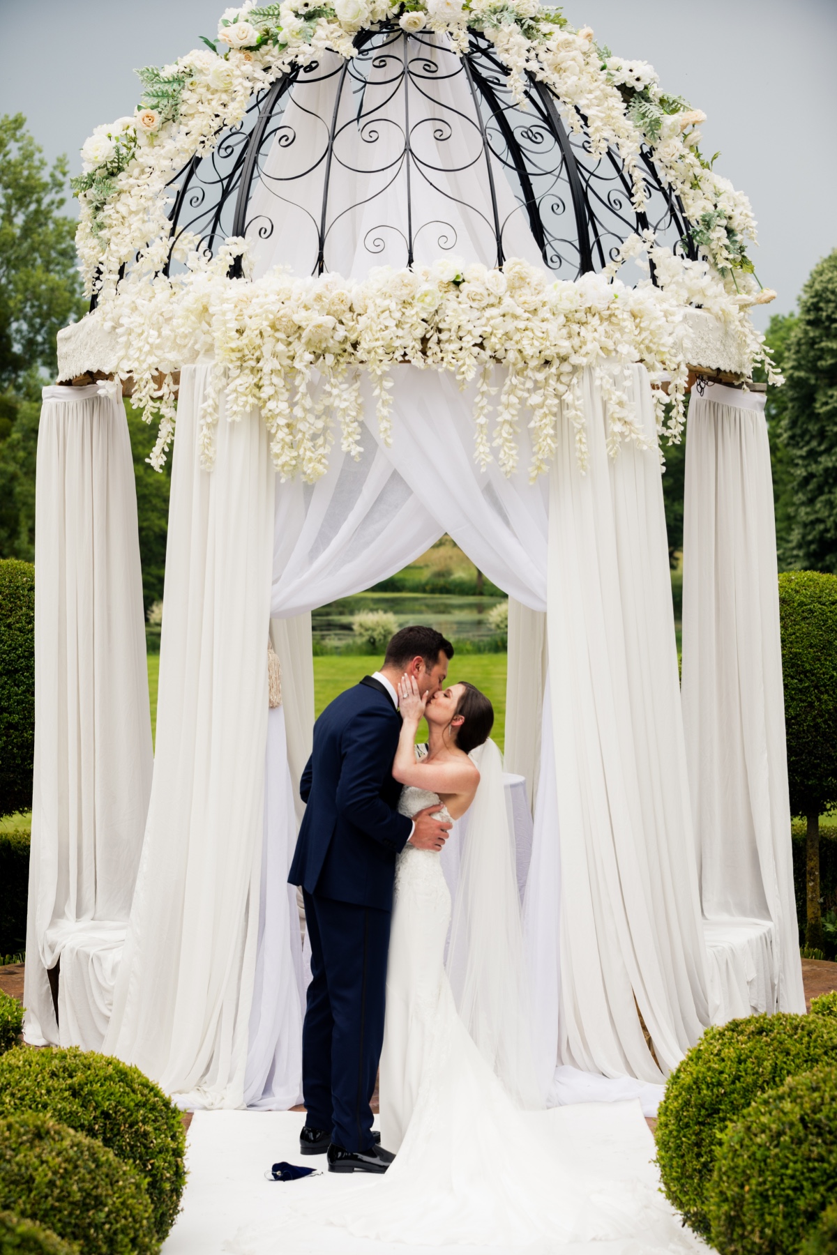Couple sharing a kiss under a white draped gazebo at a wedding