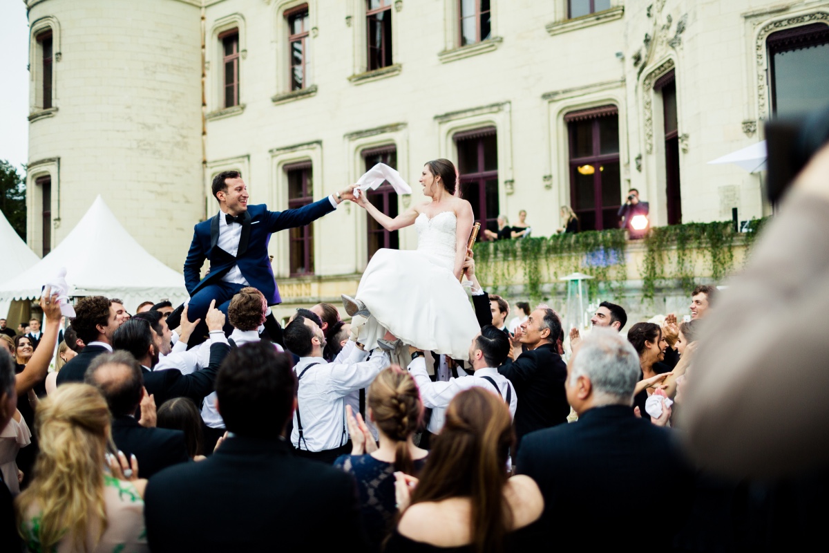 Wedding guests celebrate the bride and groom being lifted by their friends