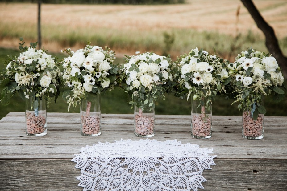 Elegant white bouquets in glass vases on a wooden table setting