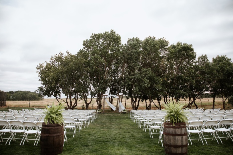 Outdoor wedding ceremony setup with white chairs under trees