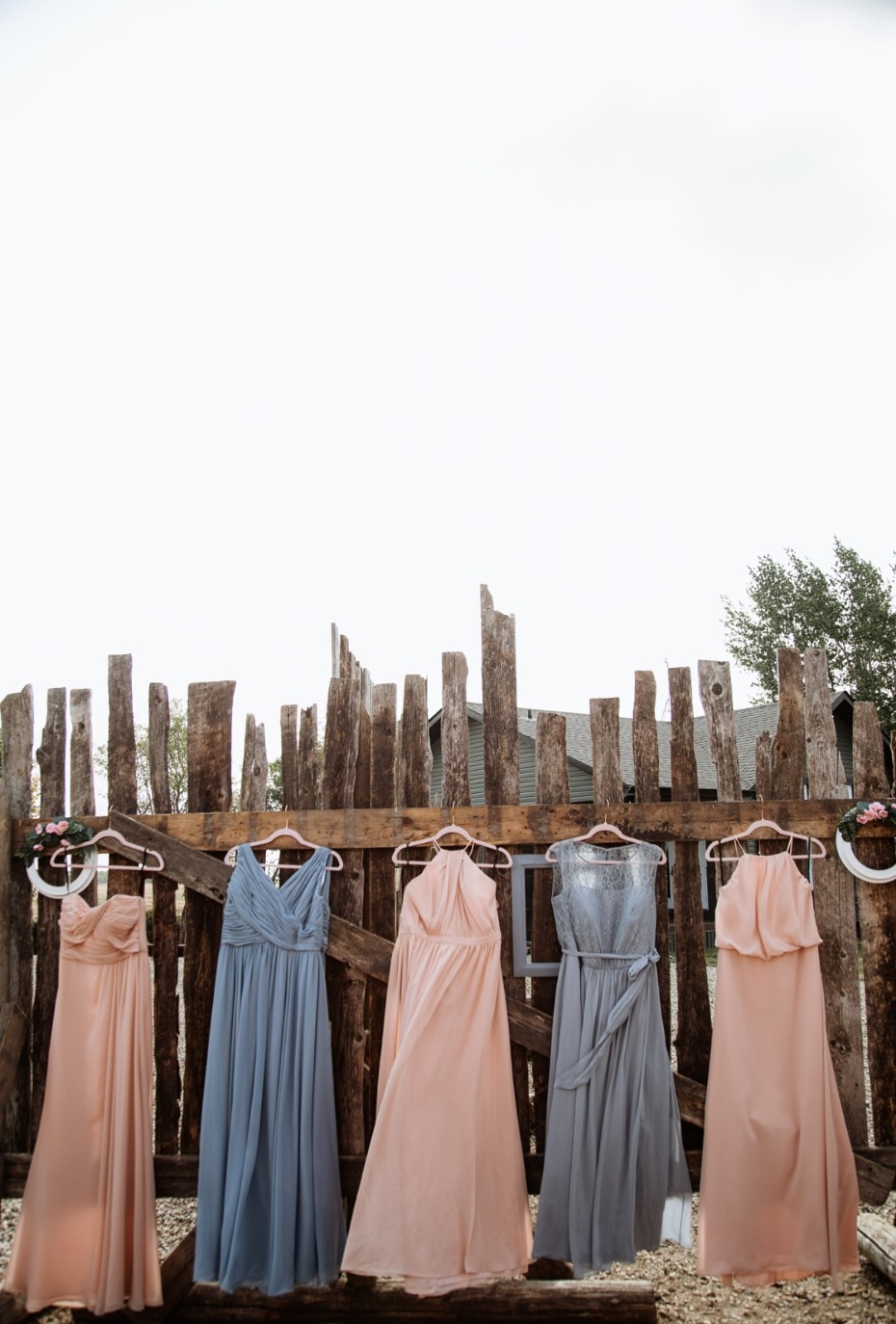Pastel bridesmaid dresses on a wooden fence for wedding
