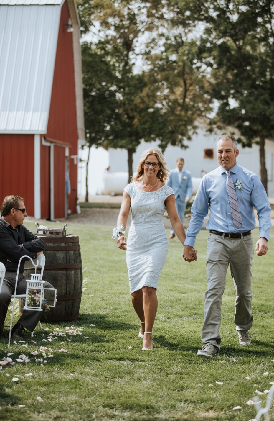 Bride and father walking down aisle toward red barn