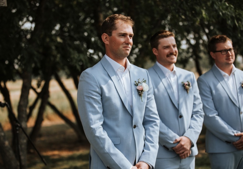 Groom and groomsmen in light blue suits at wedding