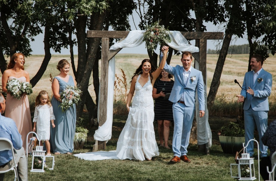 Happy couple married under rustic outdoor wedding arch