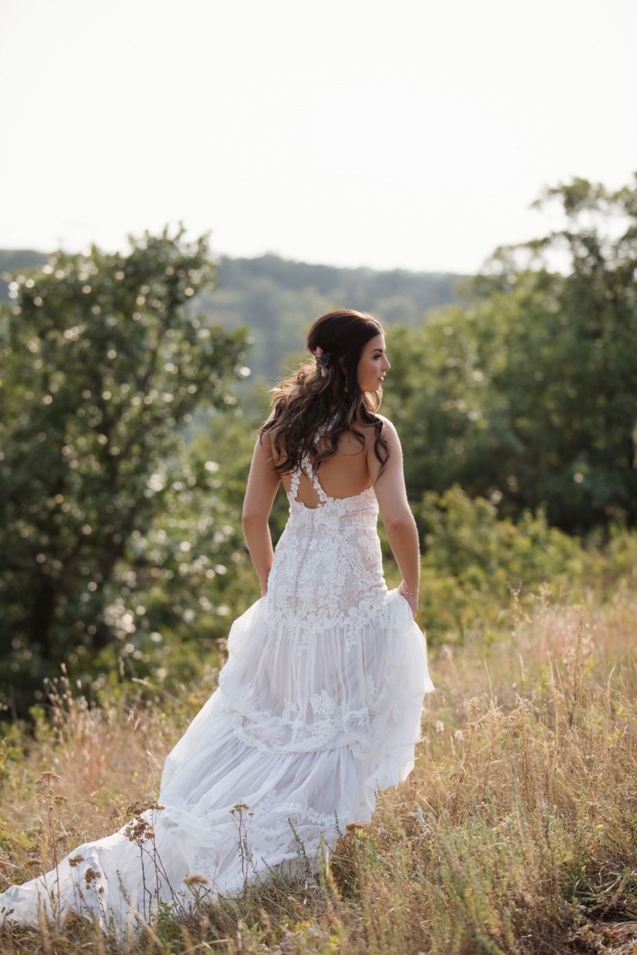 Bride in a flowing white lace wedding gown outdoors