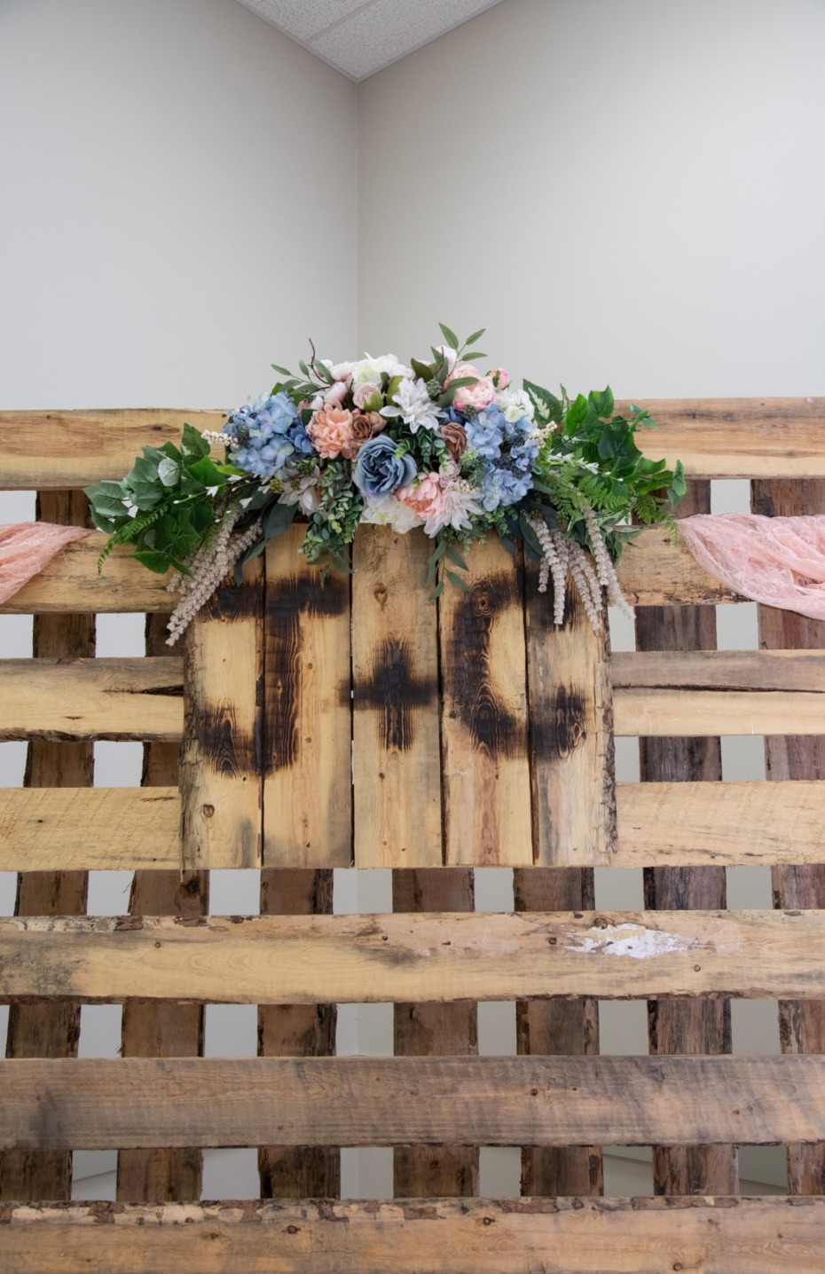Wedding floral arrangement on wooden backdrop with initials JG