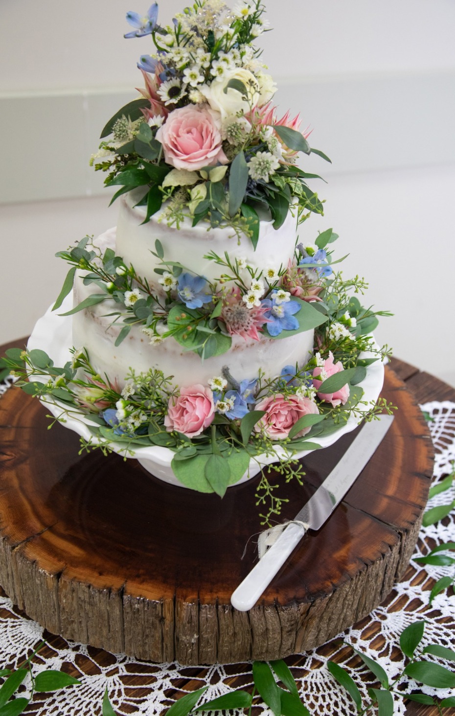 Elegant wedding cake with flowers on a rustic wooden cake stand