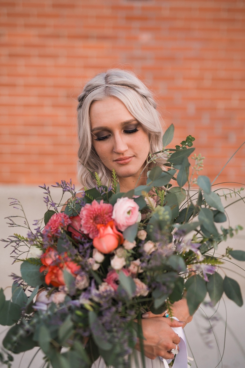Bride with stunning floral bouquet by a brick wall