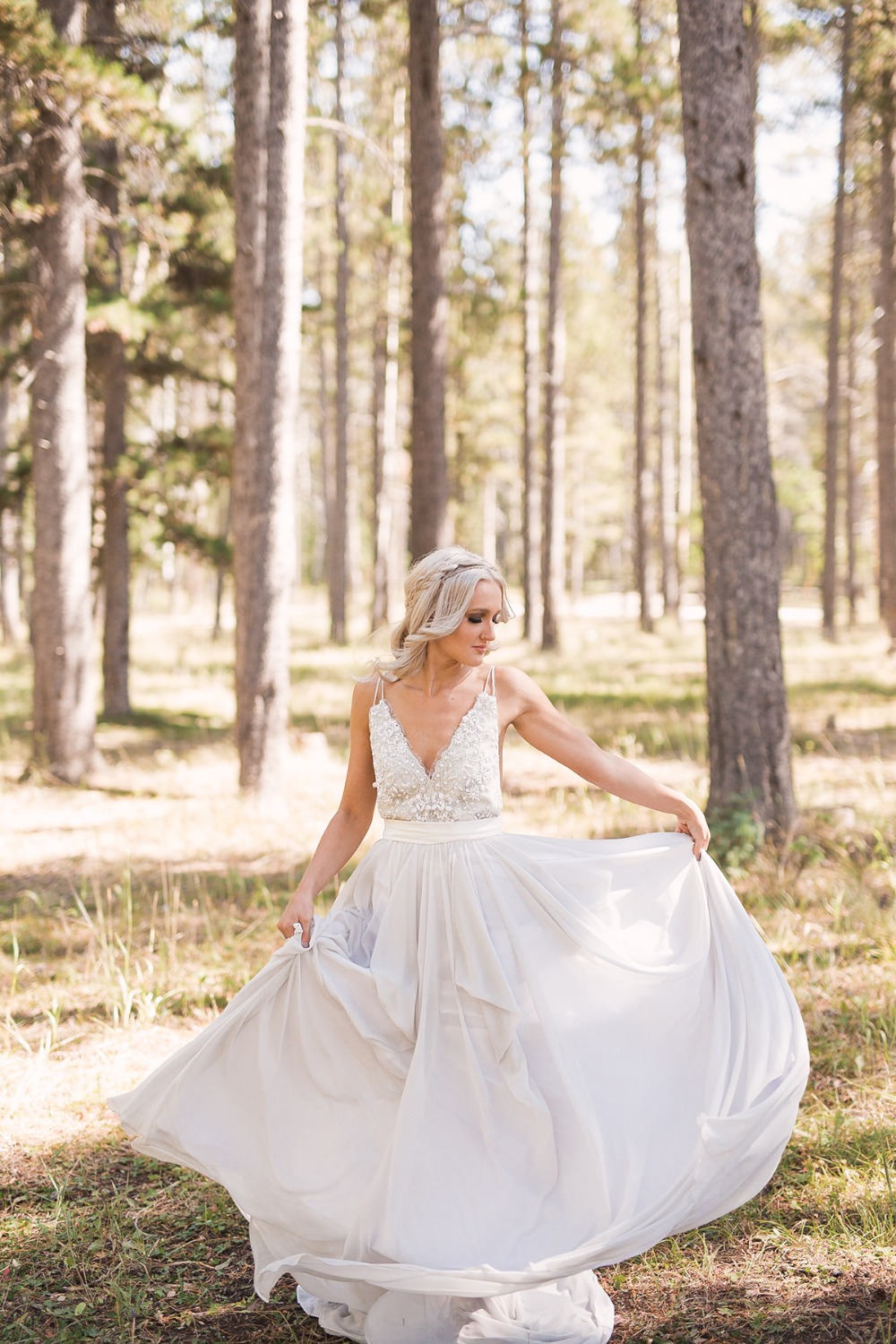 Bride twirls in forest wearing flowing white wedding gown