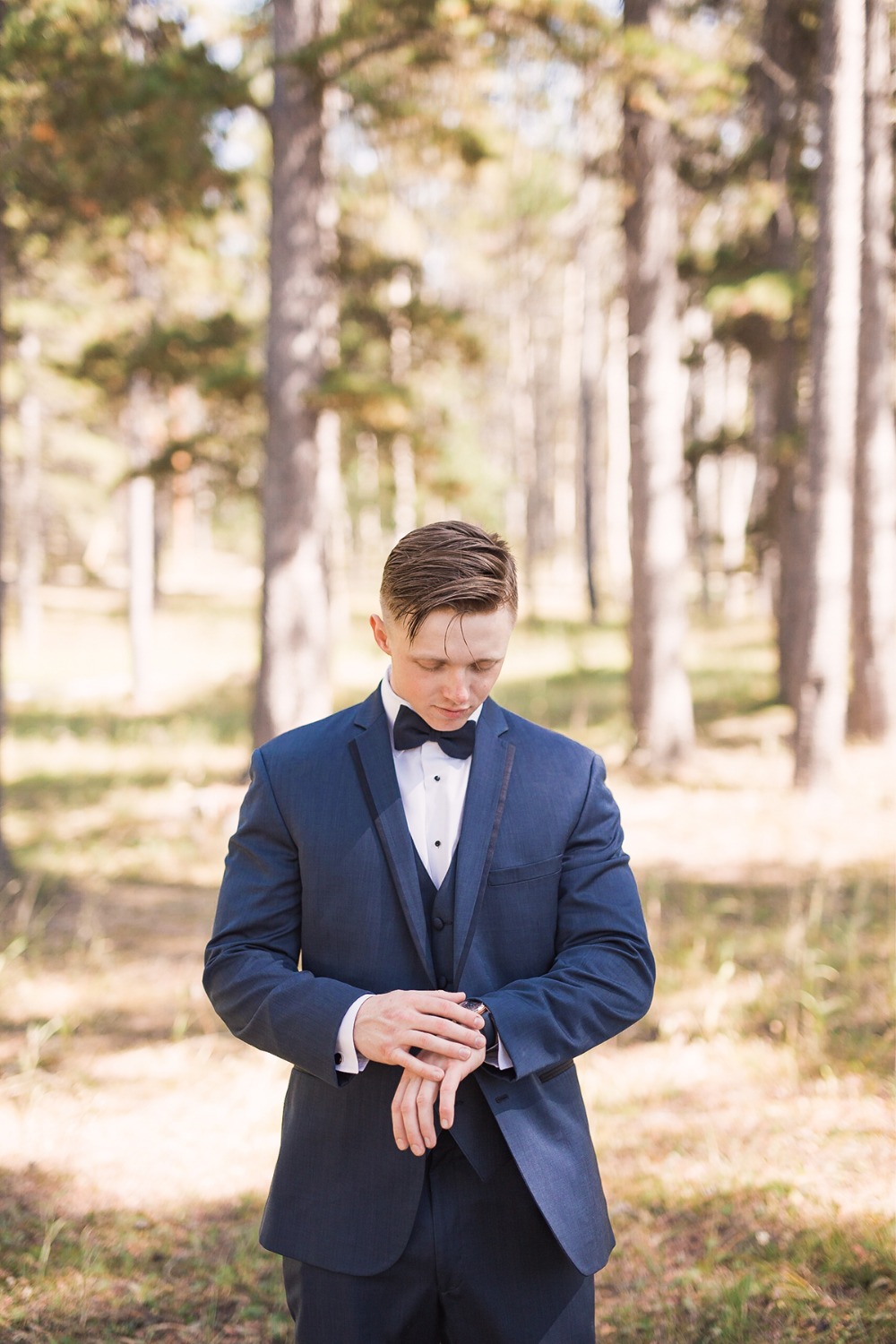 Groom in navy suit checking the time before the wedding ceremony