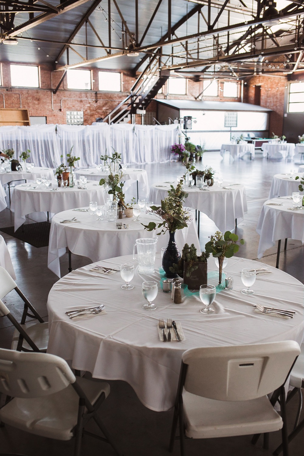 Wedding reception setup in a spacious industrial-style venue with tables