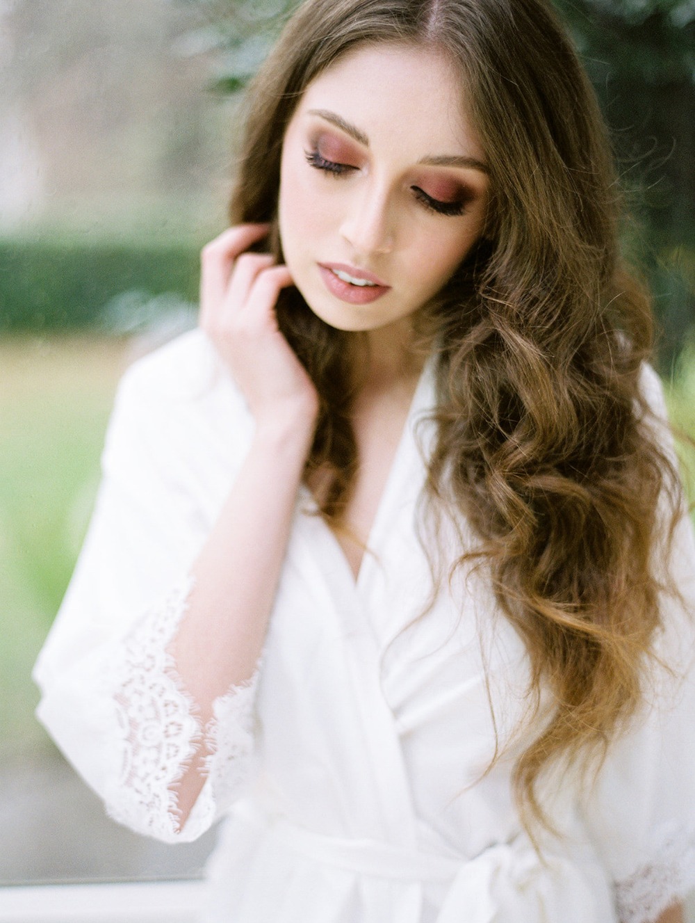 Bride in white robe with elegant makeup and wavy hair