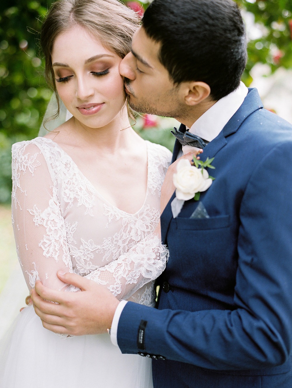 Romantic wedding moment of a groom kissing his bride on the cheek